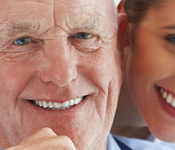 Senior adult man smiling with a mid 20's female smiling behind him